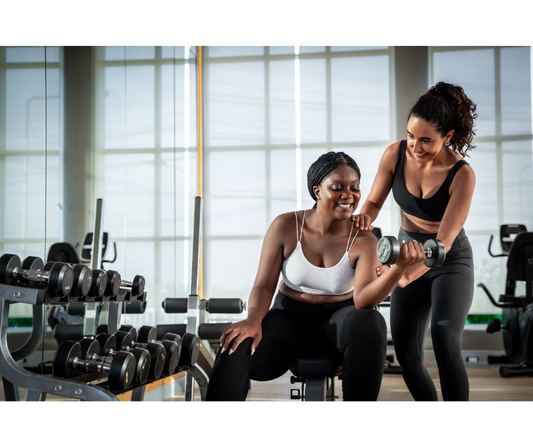 A woman sitting on a bench gets guidance from her fitness coach on how to do a bicep curl.